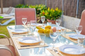 An outdoor dining table set with plates, glasses, and a bowl of lemons.