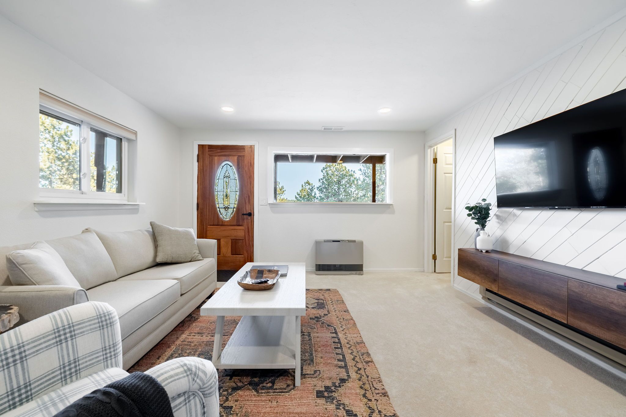 Un salon moderne avec un canapé, une table basse et un téléviseur fixé à un mur en bois.