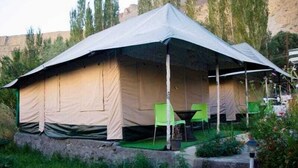 A large tent with a covered porch area, green chairs, and a small table. - Zaildar's Royal Garden Turtuk (Leh)