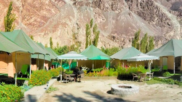 A row of tents with outdoor seating, set against a mountainous backdrop. - Zaildar's Royal Garden Turtuk (Leh)