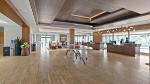 Eine geräumige Lobby mit Holzboden, einer Rezeption und einer Sitzecke mit Couchtisch.