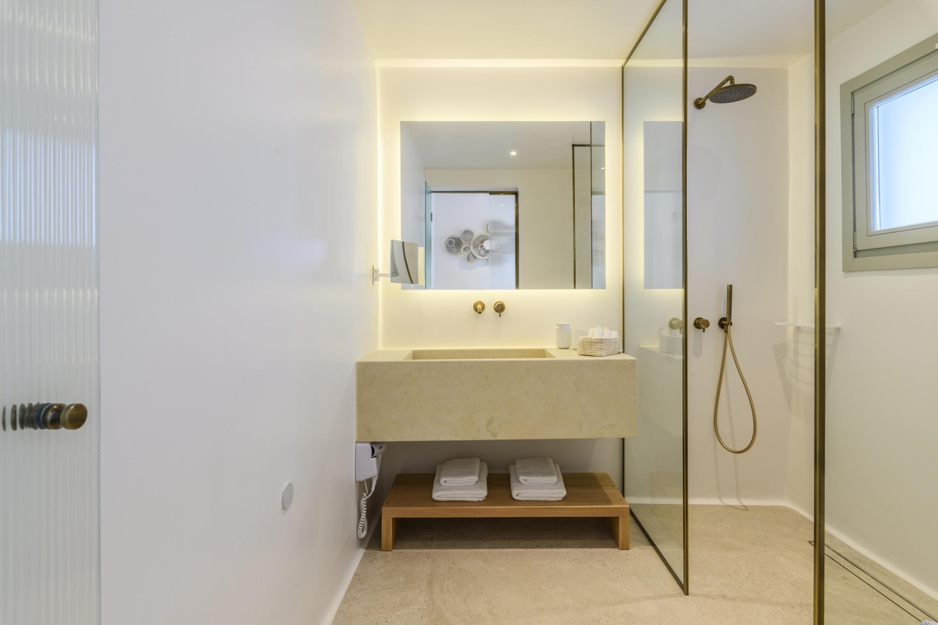 A modern bathroom with a glass shower enclosure, a beige sink, and a mirror above it.