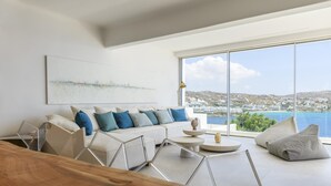 Una sala de estar moderna con un ventanal grande, un sofá blanco y una mesa de centro de madera.