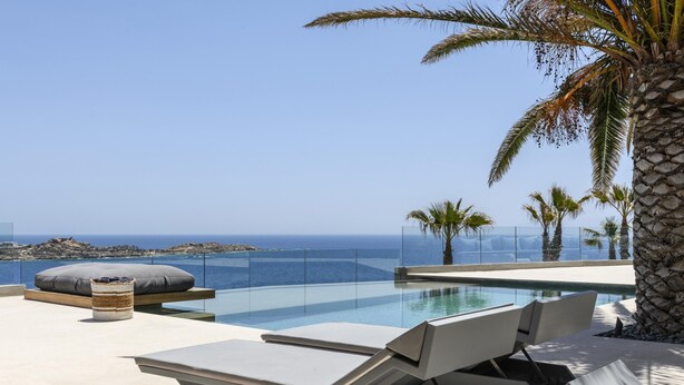 Un área de piscina moderna al aire libre con sillas de descanso y vista al mar.