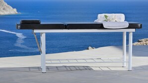 Une table de massage, agrémentée d’une serviette et de fleurs, avec vue sur la côte.