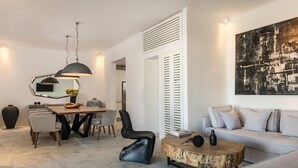 A modern living room with a dining area, a sofa, a coffee table, and a painting on the wall. - Channel I in Mykonos (Mykonos)