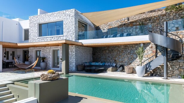 A modern house with a stone facade, a swimming pool, and a built-in outdoor seating area. - Channel I in Mykonos (Mykonos)