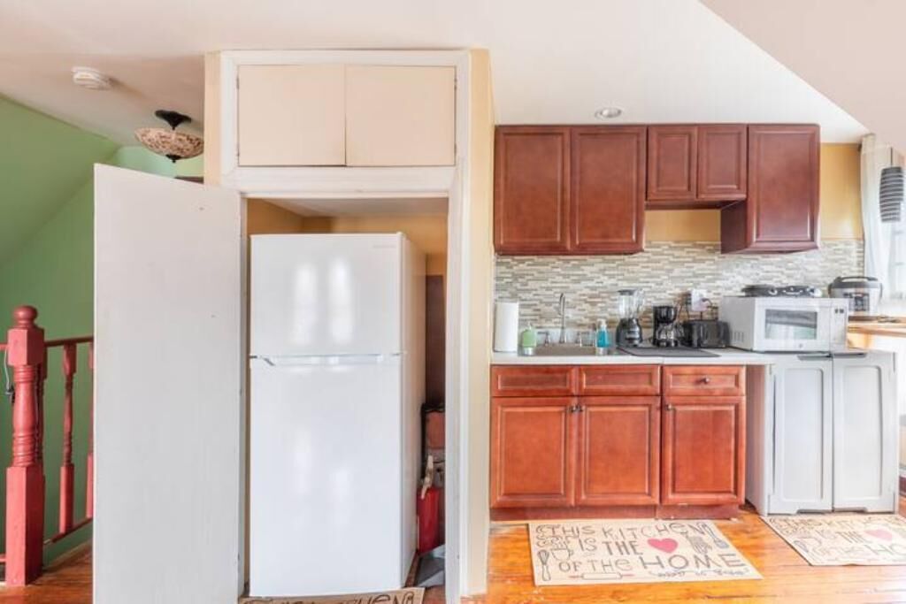 A compact kitchen with wooden cabinets, a white refrigerator, and a microwave.