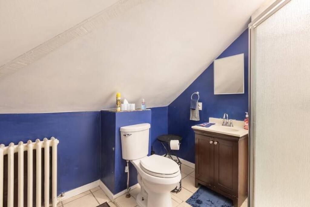 Ein kleines, kompaktes Badezimmer mit einer weißen Toilette, einem Holzschrank und einer blauen Wand.
