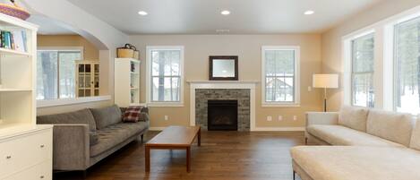 A spacious living room with hardwood flooring, a fireplace, and two sofas.