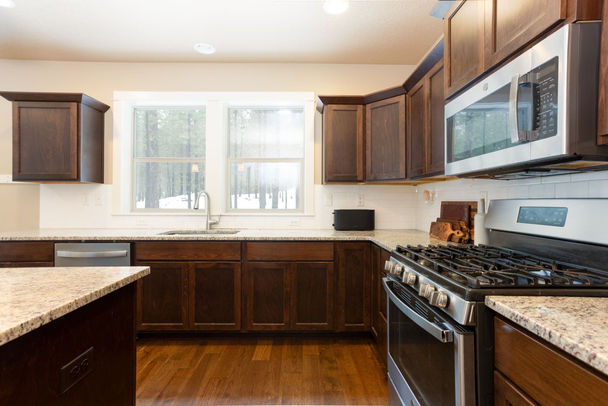 A modern kitchen with dark wooden cabinets, a stainless steel stove, and a built-in microwave.