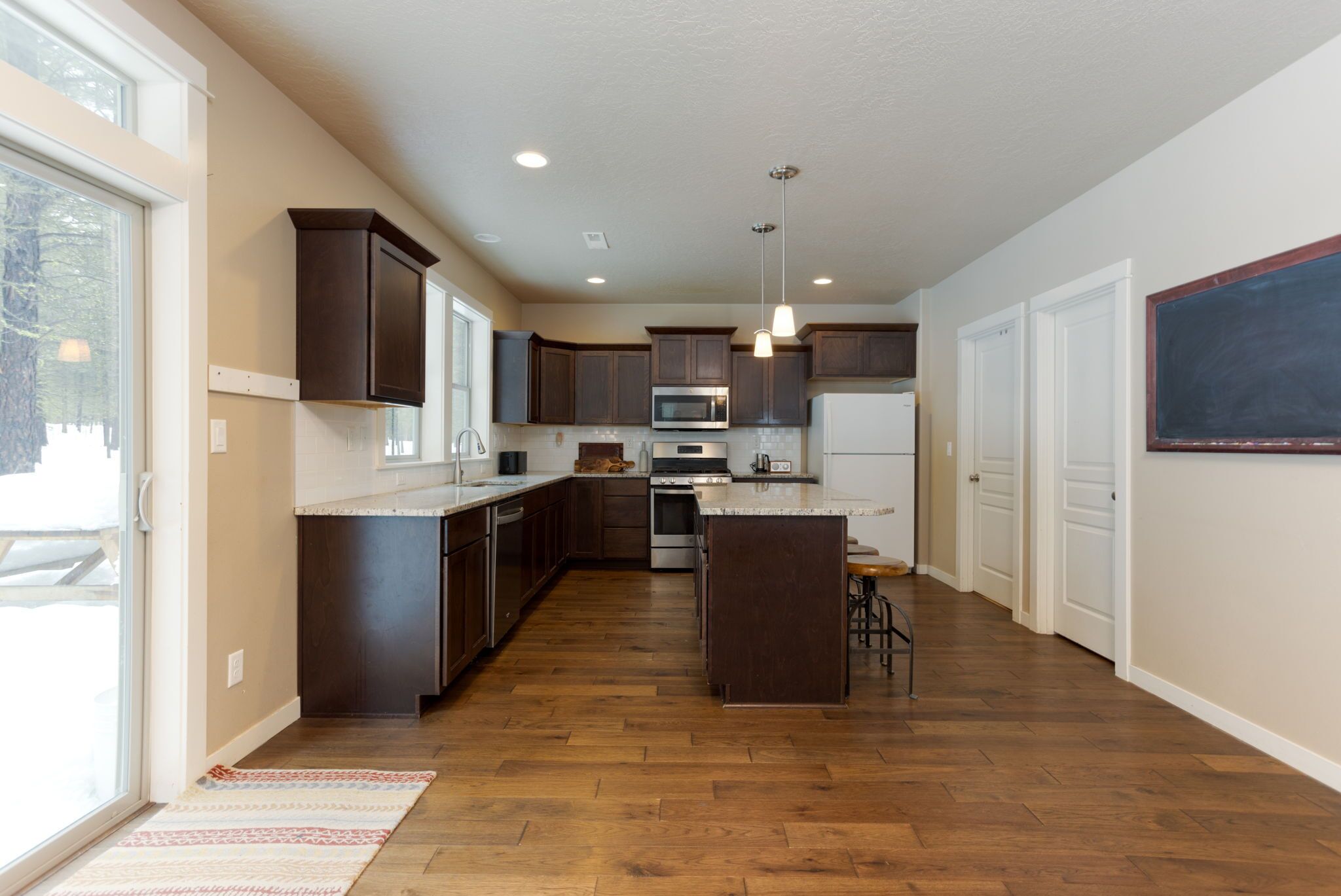 A modern kitchen with dark wooden cabinets, stainless steel appliances, and a large island.