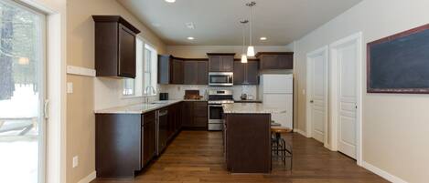 A modern kitchen with dark wooden cabinets, stainless steel appliances, and a large island.
