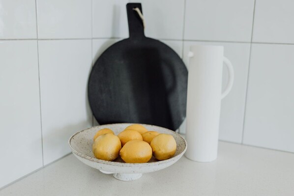 A kitchen counter with a white ceramic plate holding several lemons, a black frying pan, and a white ceramic pitcher. - Indooor & Outdoor Fireplace | Acreage | Ocean View | 10min to Australia Zoo (Mount Mellum)