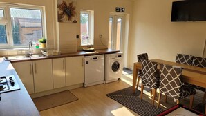 A compact kitchen with a dishwasher, a washing machine, and a dining area with a table and chairs. - 5-Bed House with separate living room (Birmingham)