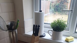 A kitchen with a stainless steel sink, a window with a view of the backyard, a potted plant, and a knife block. - 5-Bed House with separate living room (Birmingham)