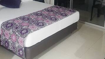 Una habitación de hotel moderna con una cama grande, una zona de escritorio separada y un ventanal corredero que da a un balcón.