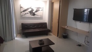 A living room with a sofa, a coffee table, a flat-screen TV mounted on the wall, and a painting on the wall. - Aparta Estudio Loft (Bucaramanga)