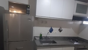A modern kitchen with a built-in microwave, stainless steel refrigerator, and a gas stove. - Aparta Estudio Loft (Bucaramanga)