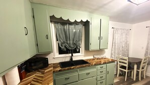 A compact kitchen with a sink, a microwave, and a dining area with a table and chairs. - Pekin Cottage (Pekin)