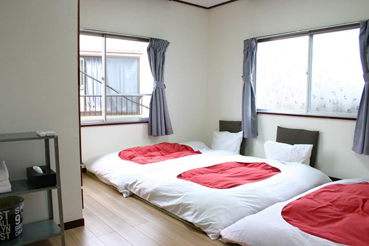 A hotel room with two beds, a small desk with a telephone, and a window with curtains.