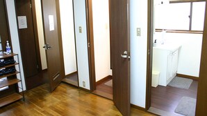 A hotel room with wooden flooring, a bathroom with a toilet and sink, and a shoe rack with shoes. - RETRO (Fujikawaguchiko)