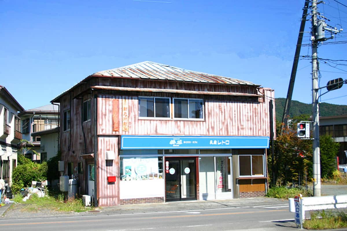 A two-story building with a blue storefront and a metal roof.