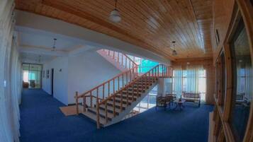 Una habitación amplia con una escalera de madera, un ventanal grande y una alfombra azul.