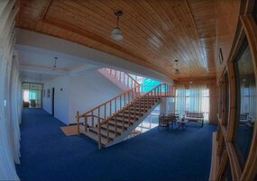 Una habitación amplia con una escalera de madera, un ventanal grande y una alfombra azul.