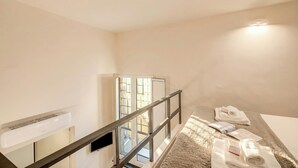 Een hotelkamer met een bed, een raam, een deur en een luchtverkoeler aan de muur.