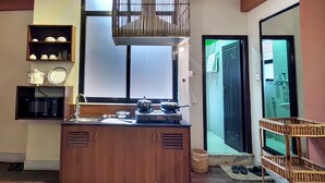 Una cocina compacta con un mueble de madera, un microondas, una estufa y una lámpara colgante.