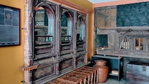 Una habitación con un armario de madera tradicional, suelo de baldosas y un ventanal con diseños elaborados.