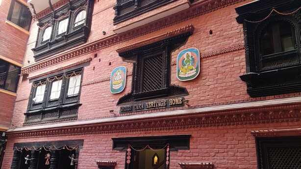 Un edificio de varios pisos con detalles arquitectónicos tradicionales, como balcones ornamentados y marcos de ventanas decorativos.