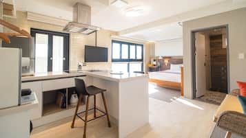 A compact kitchen with a central island, a dining area, and a bedroom with a large window.