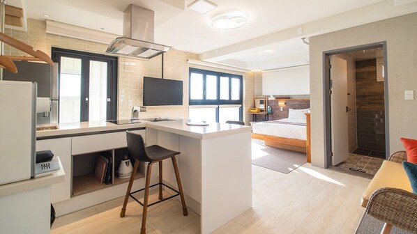 A compact kitchen with a central island, a dining area, and a bedroom with a large window. - Gyeongju Luna Piena Poolvilla (Gyeongju)