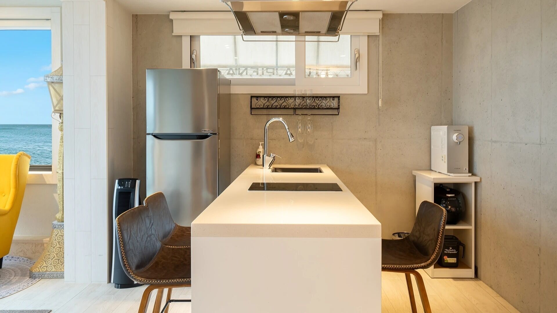 A compact kitchen with a built-in island, a stainless steel refrigerator, and a coffee machine.