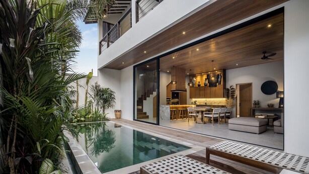 A modern house with a pool, wooden deck, and a kitchen with bar seating.