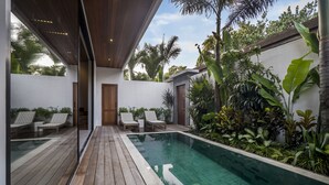 A modern outdoor pool area with wooden decking and lounge chairs.