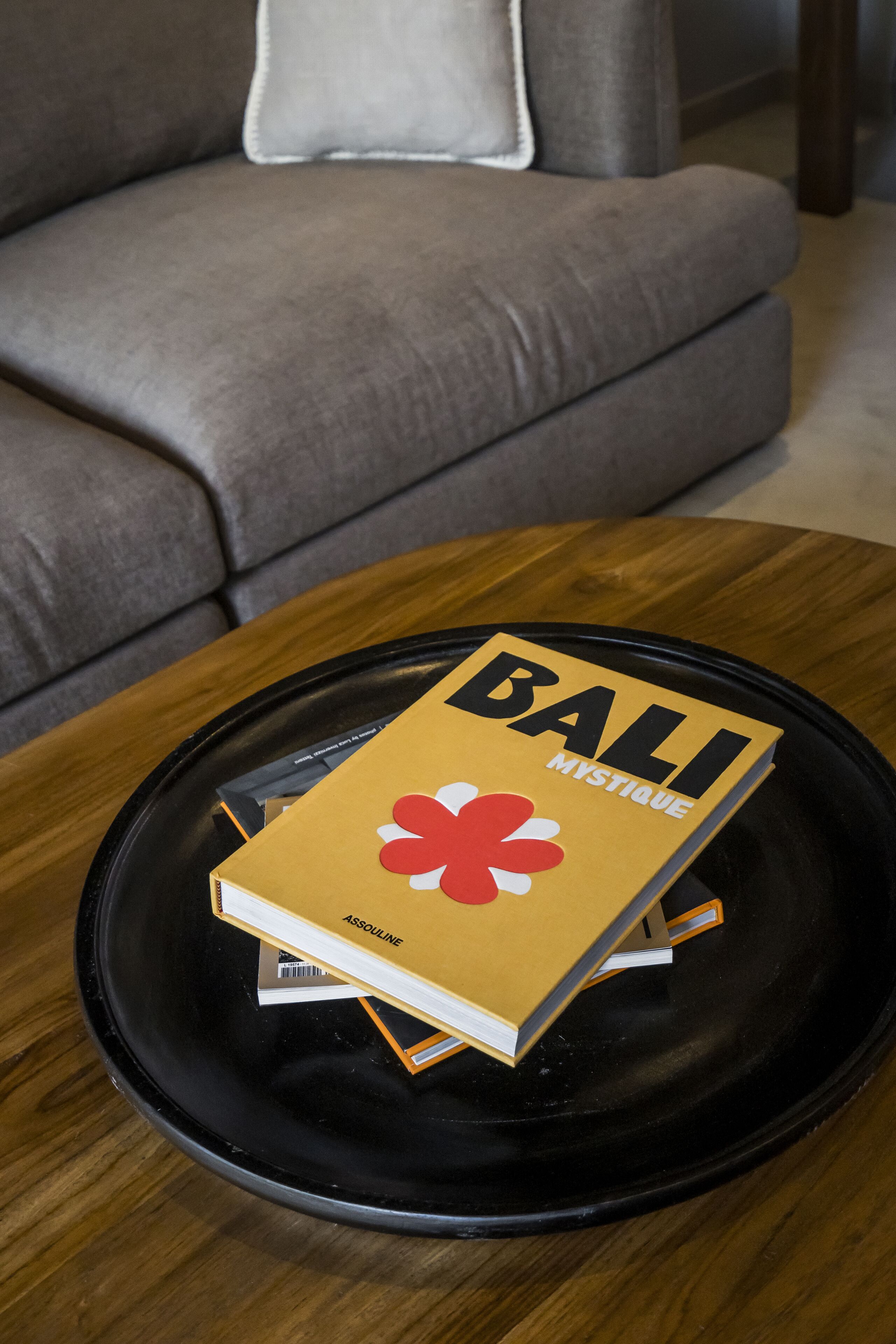 Ein Buch mit dem Titel „BALI MYSTIQUE“ auf einem schwarzen Tablett auf einem Holztisch.
