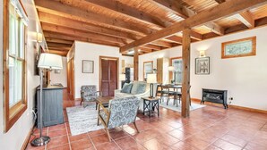 A spacious living area with wooden beams, tiled flooring, and a mix of furniture including a sofa, chairs, and a coffee table. - Pet-Friendly Cabin in Marietta w/ Porch Swings (Cleveland)