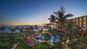 A resort with a large pool, palm trees, and a view of the ocean at dusk. - 𝐅𝐢𝐧𝐝𝐢𝐧𝐠 𝐌𝐞𝐢𝐥𝐢 Beachfront Ocean Club+Amenities. 1BR Molokai Suite (Lahaina)