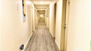Un pasillo largo y estrecho con suelo de madera y puertas a ambos lados.