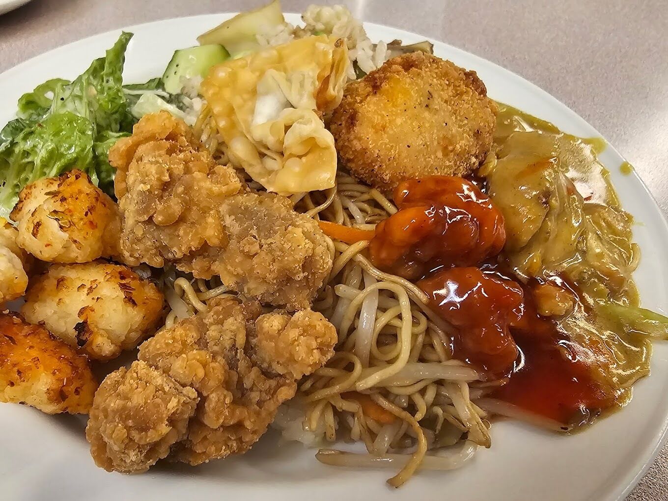 A plate of food with noodles, fried items, and vegetables.