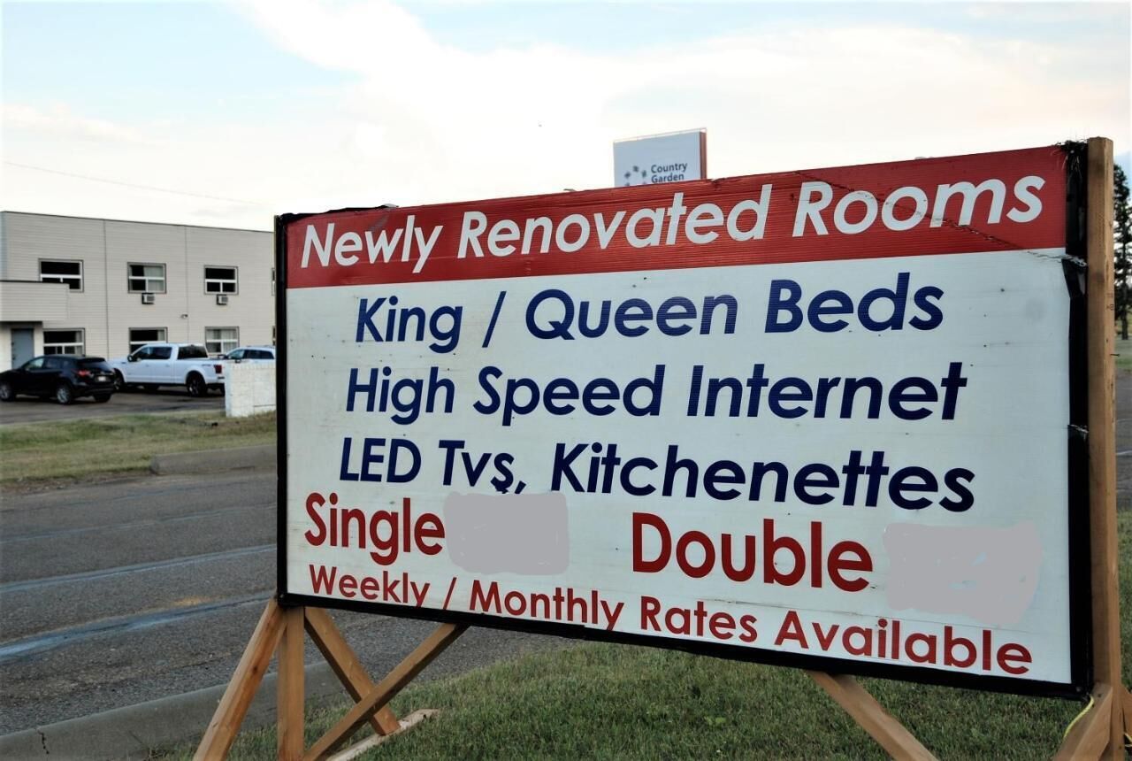 Placa anunciando quartos recém-renovados com camas king ou queen, internet de alta velocidade, televisores LED e cozinhas compactas.