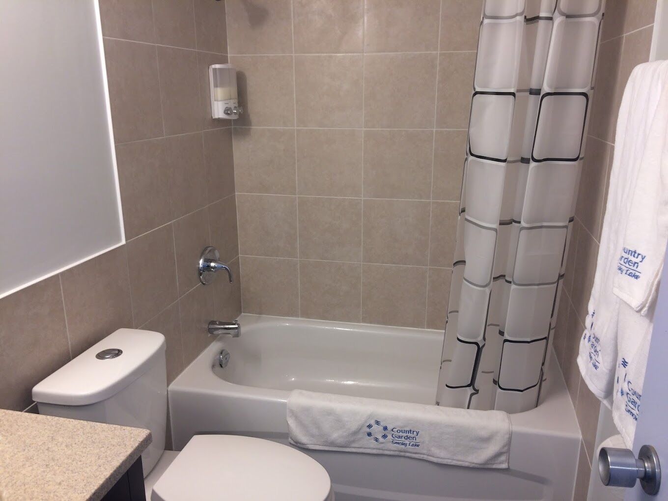 A bathroom with a bathtub, toilet, and a towel rack with a towel.