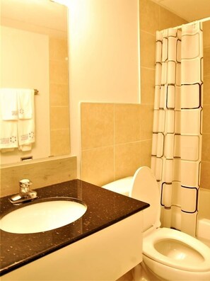 Bathroom features a sink, toilet, and shower area with a geometric-patterned shower curtain.