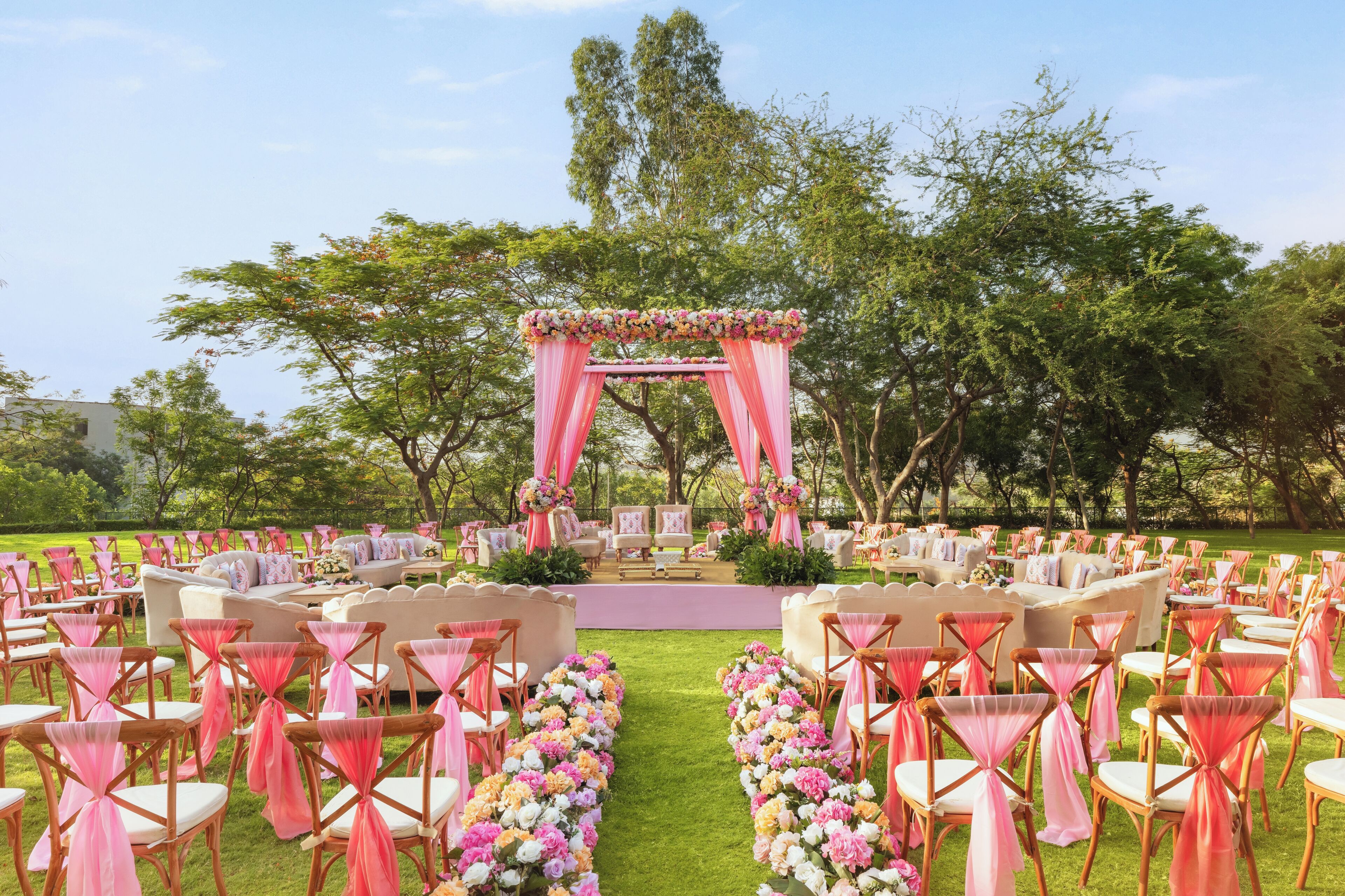 Un lugar para bodas al aire libre con un arco floral, filas de sillas y una zona de asientos centrales.