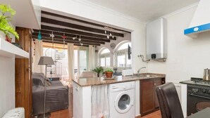 A compact kitchen with a washing machine, a stove, and a dining area with a table and chairs. - Casa El Encanto, overlooking the sea. (Conil de la Fra.)