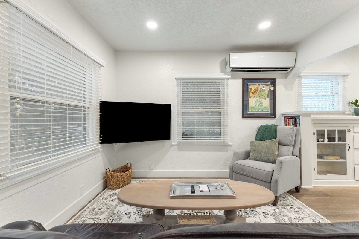 A living room with a sofa, a coffee table, a TV mounted on the wall, and a fireplace with a bookcase.