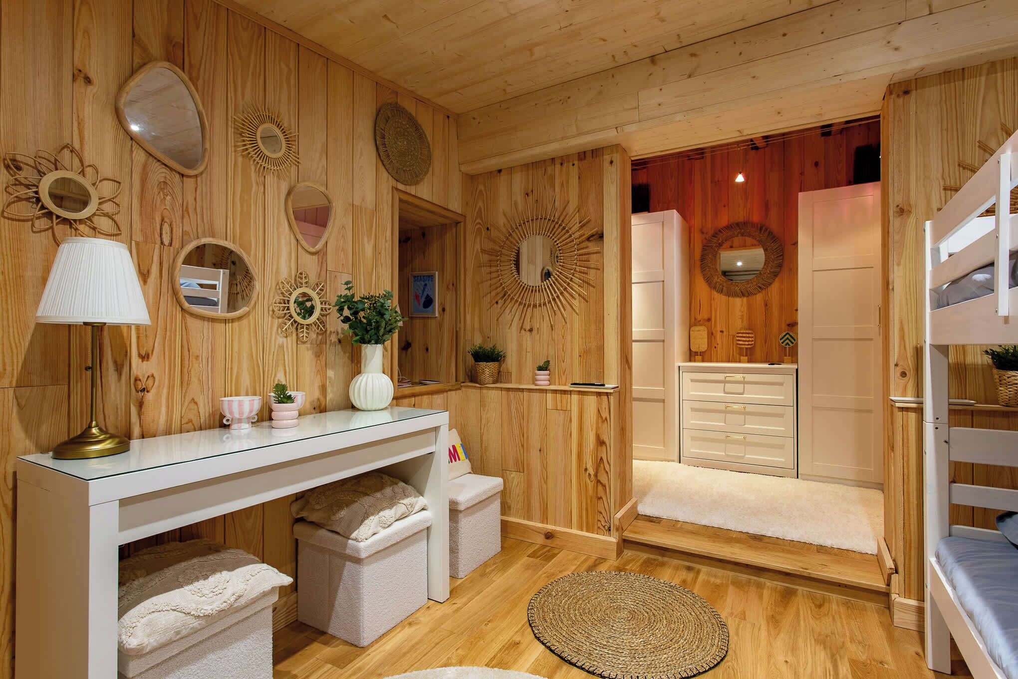 A wooden interior with a bunk bed, a vanity with a mirror, a lamp, and storage boxes.